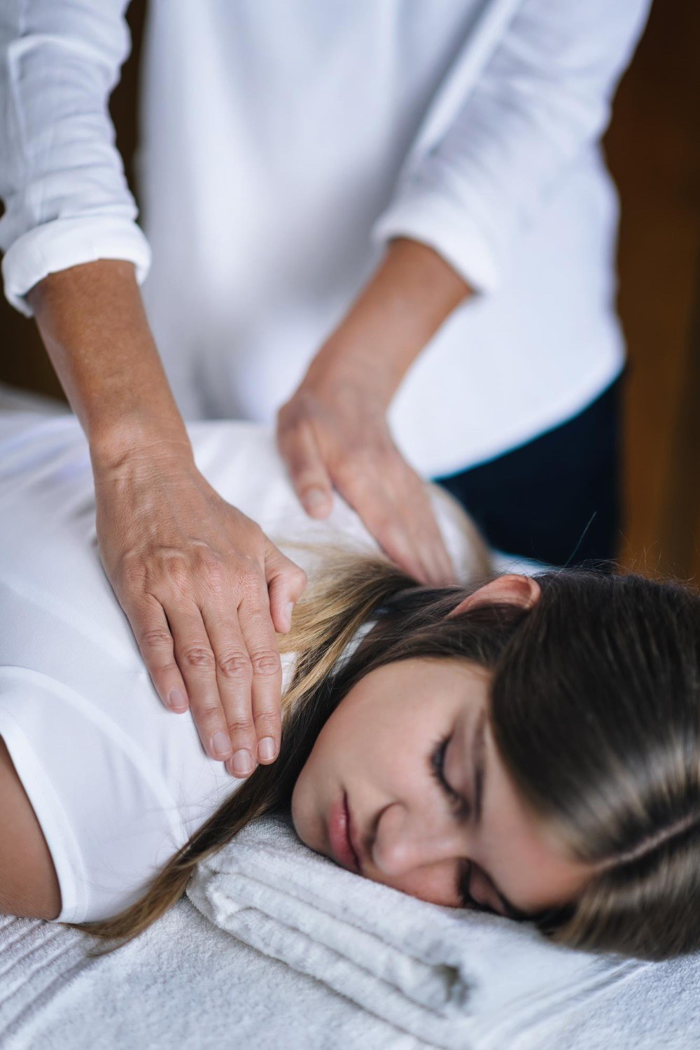 Reiki alkalom: gyengéd kéztartás egy pihenő résztvevő vállánál.